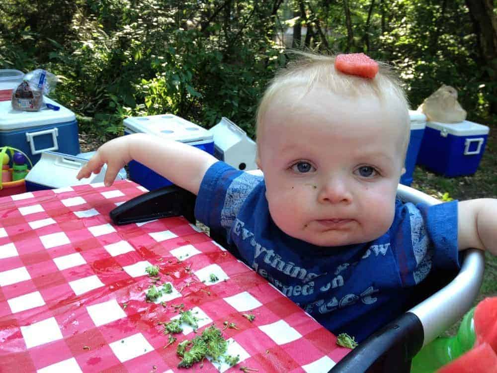 baby sitting in clip on chair while camping