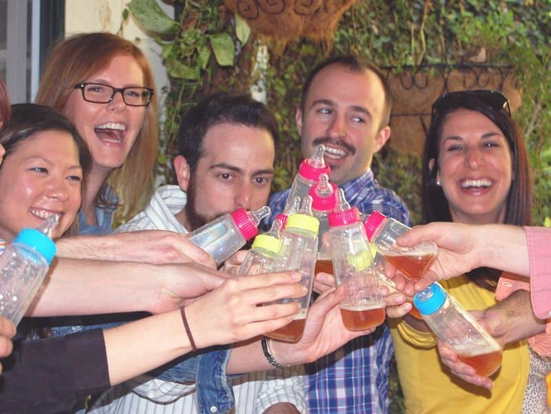 men and women at a baby shower with beer in baby bottles