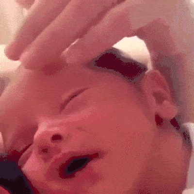 newborn baby smiling while having his head rubbed