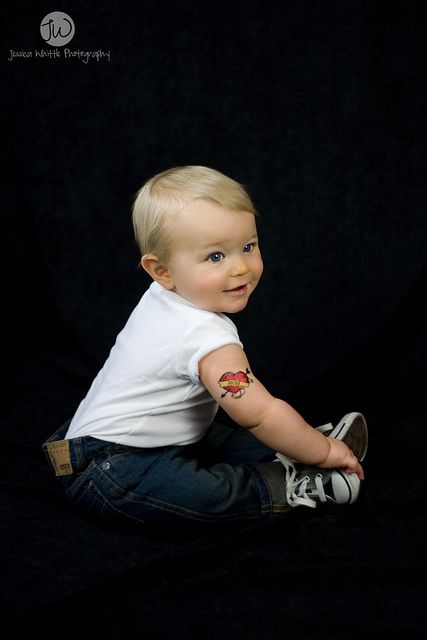 toddler sitting on floor with temporary mom tattoo on their arm