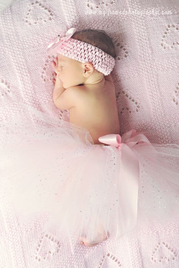 Baby sleeping on soft pink blanket with pink tutu and pink headband