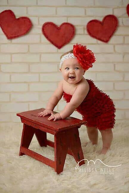 baby standing next to red stool with heart decor for Baby's First Valentine's Day Photo shoot