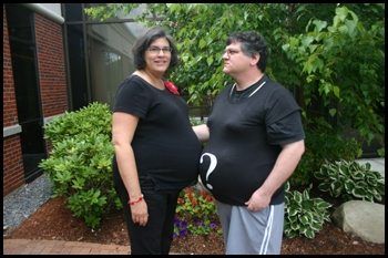 Couple stands facing one another. Both wear black t-shirts, hers plain, his with a question mark on it.