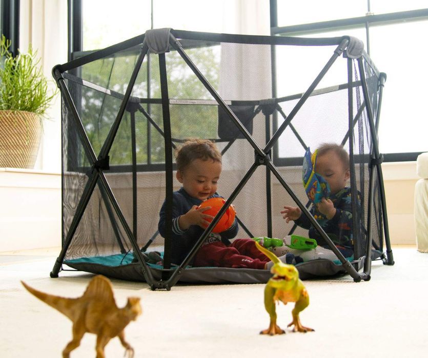 two babies playing in a travel playard