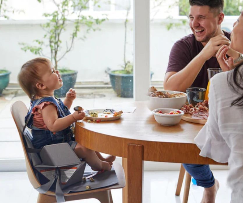 Baby sitting in a Bombol Popup eating at a table with parents