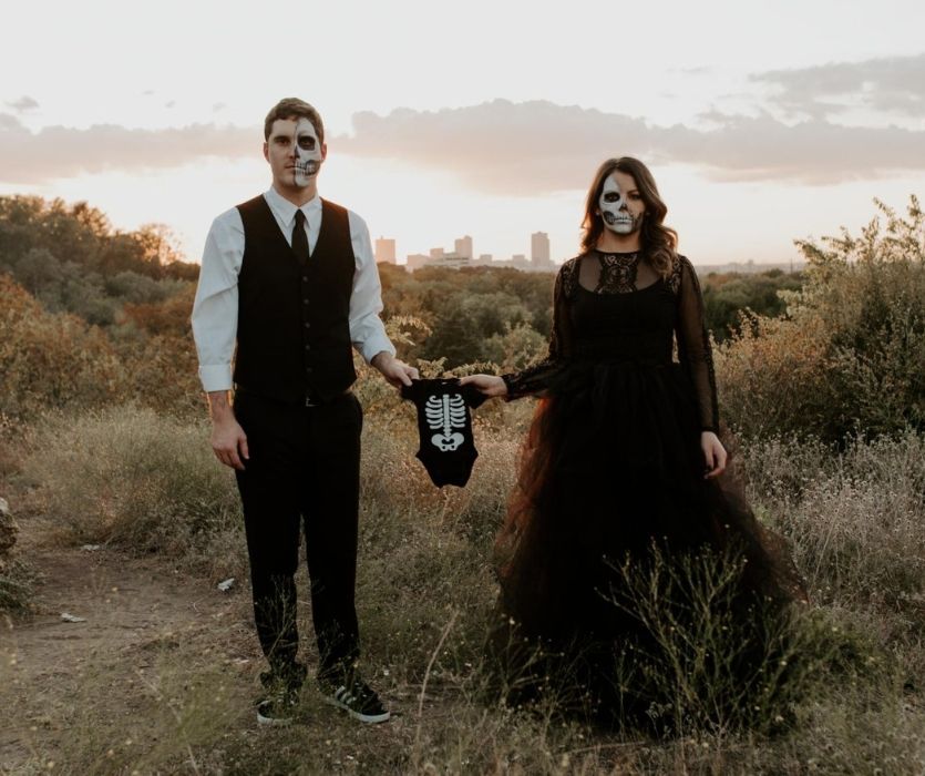 couple in skeleton halloween costumes with a black baby onesie