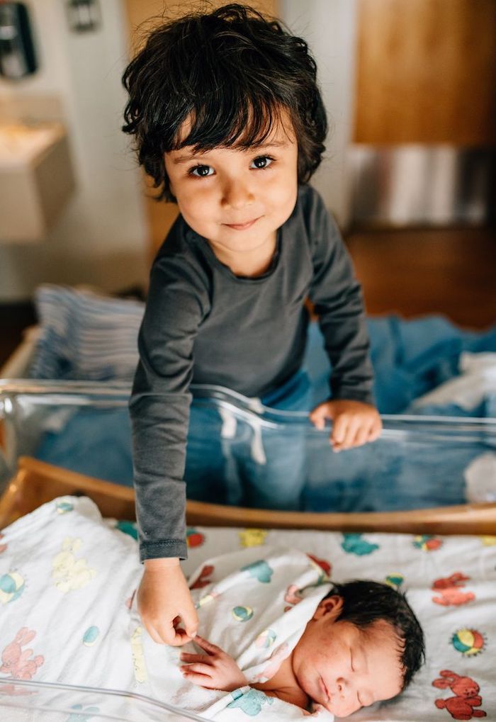 Big Brother at hospital touching finger of newborn baby