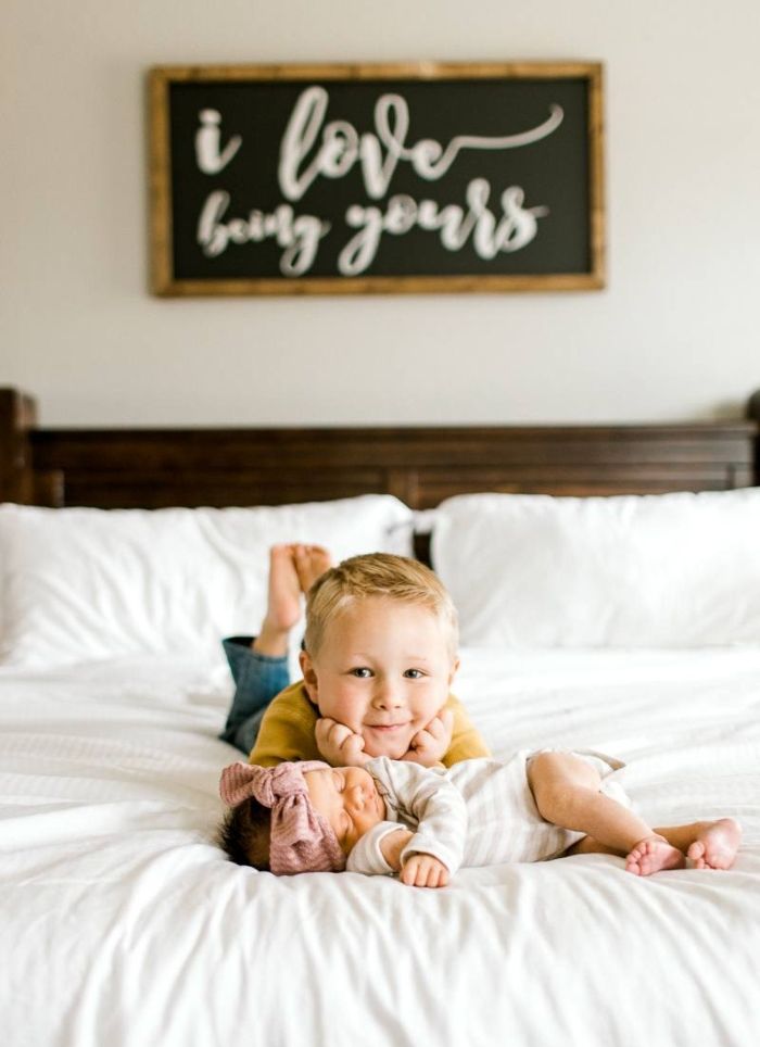 Big brother and newborn baby sister posing on bed