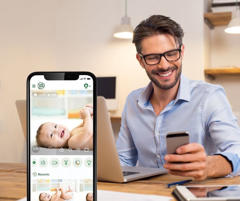 dad looking at smart phone of baby monitor feed at work