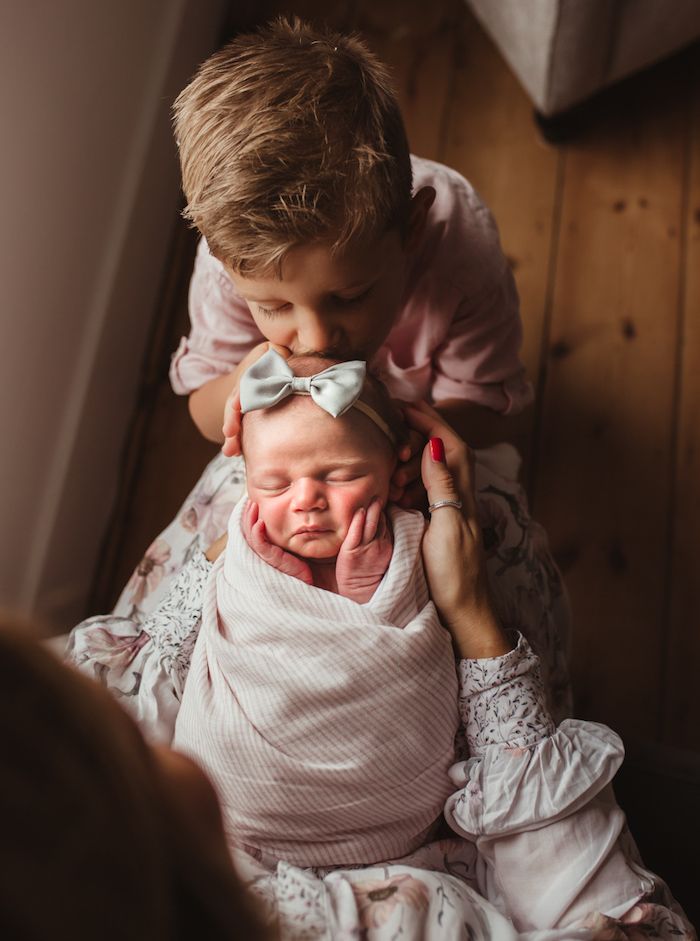 Big brother kissing new baby sister on her head