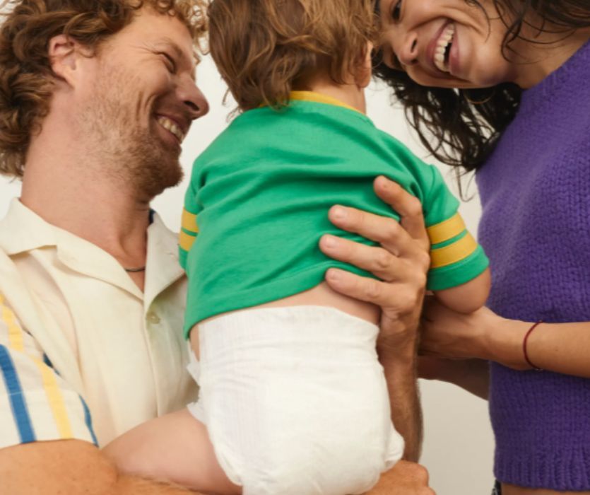 mom and dad holding baby wearing coterie diapers